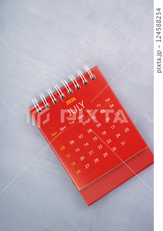July 2026 red color calendar on wooden background. 124588254