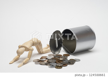 貯金箱からこぼれたコインと落ち込む人形 124588661