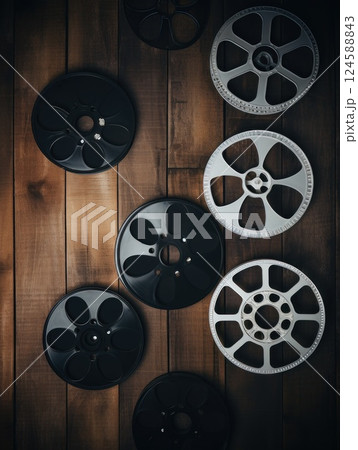 Vintage film reels displayed on a weathered wooden surface, evoking a sense of nostalgia and connection to the world of cinema and filmmaking Vintage film reels displayed on a weathered wooden surface, evoking a sense of nostalgia and connection to the world of cinema and filmmaking 124588843