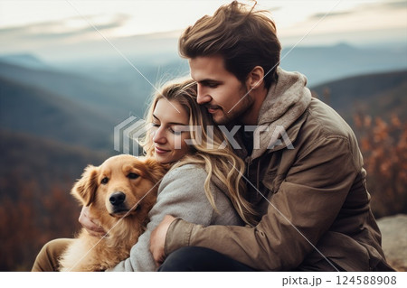 Happy young couple hiking in the mountains with their golden retriever dog, creating beautiful memories in nature 124588908