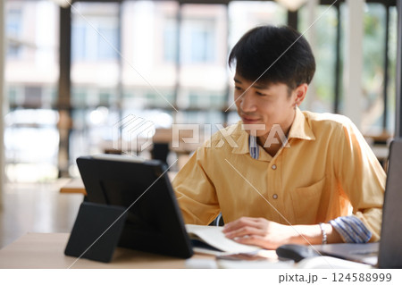 Student studying online and preparing for exams with digital devices and books 124588999
