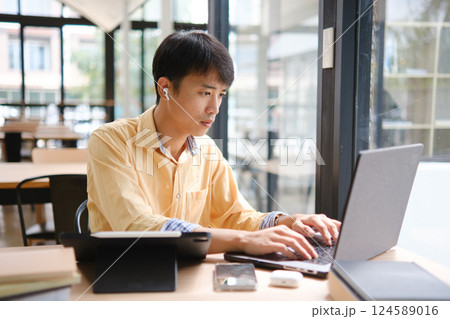 Student studying online and preparing for exams with digital devices and books Student studying online and preparing for exams with digital devices and books 124589016