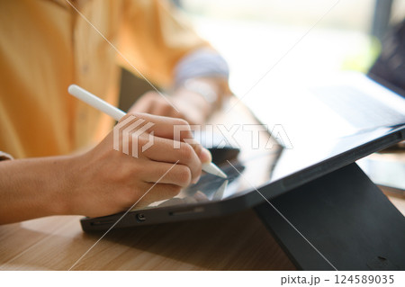 Male web designer drawing with graphic tablet at table in office. Male web designer drawing with graphic tablet at table in office. 124589035