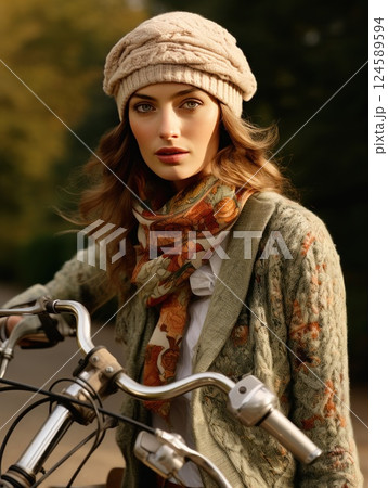 Chic woman with cap and scarf grins as she rides a vintage motorcycle down a charming cobblestone street flanked by autumn trees and lovely buildings 124589594