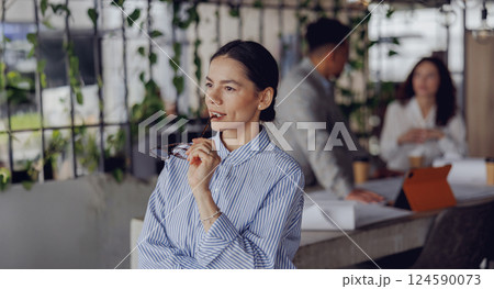 A Thoughtful Businesswoman Engaged in a Modern Office Environment, Reflecting and Collaborating 124590073