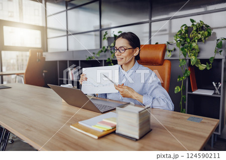 A Professional Woman Focused on Her Work at an Office Desk Surrounded by Presentation Materials A Professional Woman Focused on Her Work at an Office Desk Surrounded by Presentation Materials 124590211