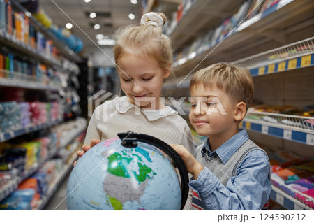 Little children choosing globe earth model at stationery store Little children choosing globe earth model at stationery store 124590212