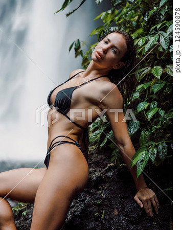 Sexy fashionable woman enjoying near waterfall. Sexy girl posing on waterfall 124590878