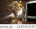 A beautiful striped cat stands on a table near a bouquet of flowers, sniffing the flowers with interest 124591035