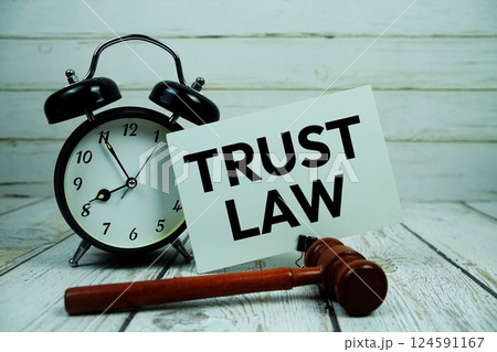 Trust Law text on paper card with alarm clock and wooden judge gavel on wooden background Trust Law text on paper card with alarm clock and wooden judge gavel on wooden background 124591167