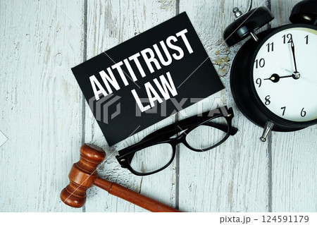 Antitrust Law text message on paper card with wooden gavel and alarm clock on wooden background Antitrust Law text message on paper card with wooden gavel and alarm clock on wooden background 124591179