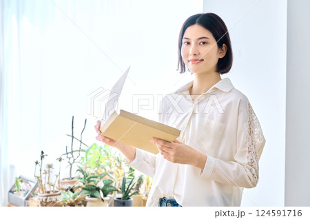 部屋で通販の荷物を確認をする主婦のライフスタイルイメージ 部屋で通販の荷物を確認をする主婦のライフスタイルイメージ 124591716