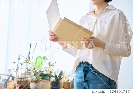部屋で通販の荷物を確認をする主婦のライフスタイルイメージ 部屋で通販の荷物を確認をする主婦のライフスタイルイメージ 124591717