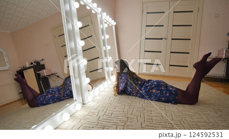 The girl is lying in front of the mirrors and flirting with herself. Manufacture of make-up mirrors. 124592531