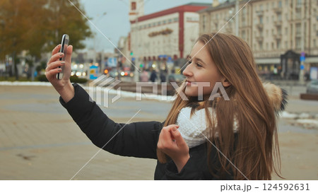 Young beautiful girl in jacket does selfi autumn in one of the city streets. Young beautiful girl in jacket does selfi autumn in one of the city streets. 124592631
