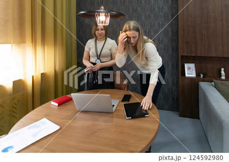Women collaborating in a modern workspace while preparing for a meeting in a cozy interior setting 124592980