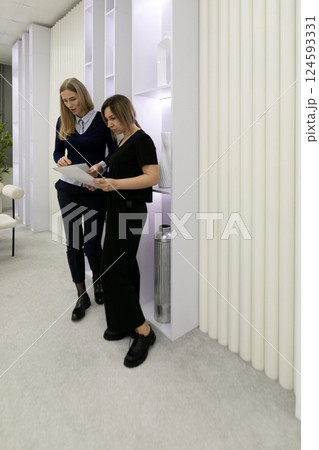 Two professional women discussing plans in a modern office setting with minimalist design and soft Two professional women discussing plans in a modern office setting with minimalist design and soft 124593331