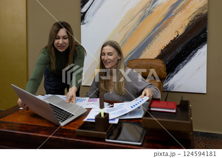 Two women collaborating in an office setting, reviewing reports and discussing strategies for a 124594181