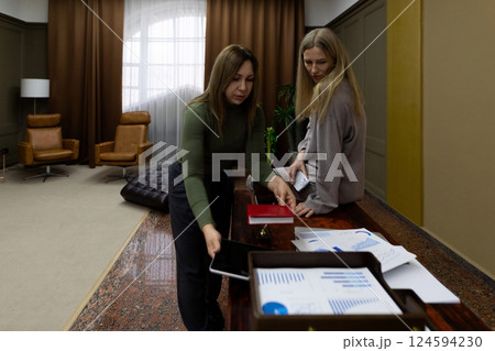 Two women collaborating on a business project in an office setting during daytime 124594230