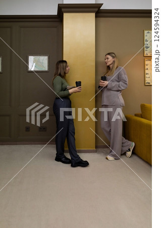 Friends engage in conversation while enjoying coffee in a stylish, cozy interior space during 124594324