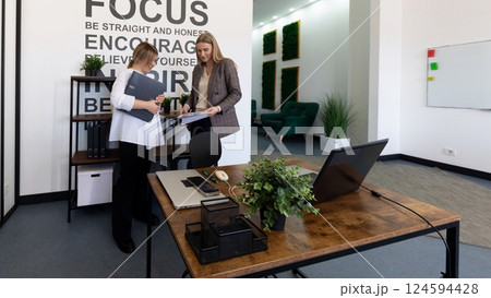 Two professionals collaborate in a modern office space promoting focus and encouragement 124594428