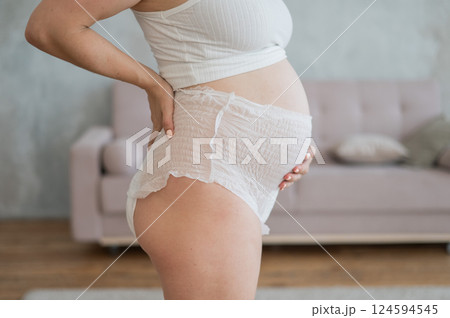 Caucasian pregnant woman in adult diapers suffers from incontinence. Close-up of belly. Caucasian pregnant woman in adult diapers suffers from incontinence. Close-up of belly. 124594545