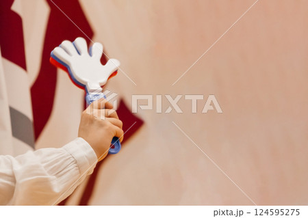 A fan's sports toy is a noisy hand with fingers in a woman's hand, red-white-blue on a beige background. 124595275