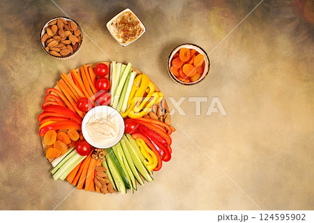 Hummus platter with appetizers, healthy food kitchen background with hummus bowl and raw vegetable sticks, nuts and dried apricots. Middle East plate, traditional vegan appetizers, oriental cuisine 124595902