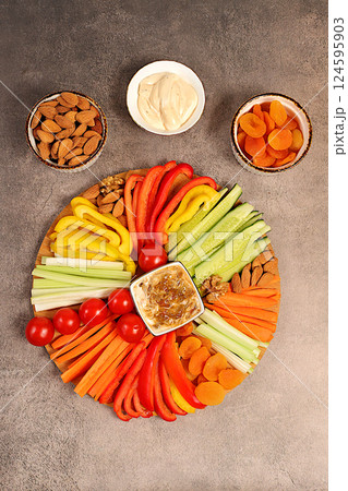 Middle East plate, Healthy food cuisine background with hummus bowl and raw vegetable sticks, nuts and dried apricots. Hummus platter with appetizers, traditional vegan snacks, oriental cuisine Middle East plate, Healthy food cuisine background with hummus bowl and raw vegetable sticks, nuts and dried apricots. Hummus platter with appetizers, traditional vegan snacks, oriental cuisine 124595903