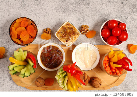 Middle East plate, Healthy food cuisine background with hummus bowl and raw vegetable sticks, nuts and dried apricots. Hummus platter with appetizers, traditional vegan snacks, oriental cuisine 124595908