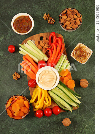 Healthy food kitchen background with hummus bowl and raw vegetable sticks, nuts and dried apricots. Hummus platter with appetizers, Middle Eastern plate, traditional vegan snacks, oriental cuisine Healthy food kitchen background with hummus bowl and raw vegetable sticks, nuts and dried apricots. Hummus platter with appetizers, Middle Eastern plate, traditional vegan snacks, oriental cuisine 124595909