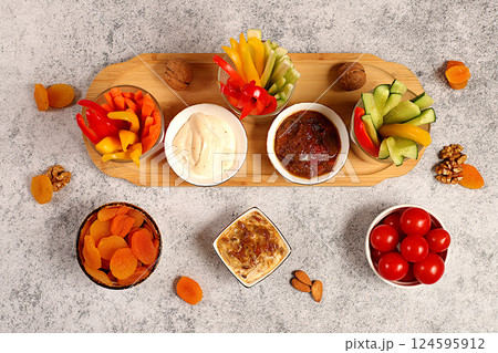 Oriental cuisine and healthy snack concept, Healthy food kitchen background with hummus bowl and raw vegetable sticks, nuts and dried apricots. Hummus platter with appetizers, traditional vegan Oriental cuisine and healthy snack concept, Healthy food kitchen background with hummus bowl and raw vegetable sticks, nuts and dried apricots. Hummus platter with appetizers, traditional vegan 124595912