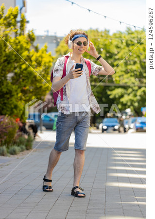 Happy tourist man in wireless headphones choosing, listening favorite music dancing outdoors street Happy tourist man in wireless headphones choosing, listening favorite music dancing outdoors street 124596287