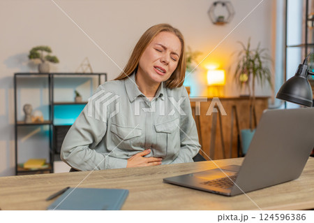 Disappointed mature Caucasian woman feeling overeating during work process on laptop in home office Disappointed mature Caucasian woman feeling overeating during work process on laptop in home office 124596386
