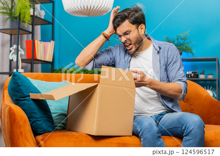 Angry dissatisfied shopper Indian man unpacking parcel feeling upset, confused, wrong delivery 124596517