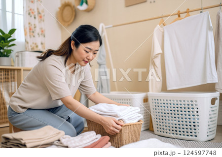 Woman Folding Laundry in a Cozy, Organized Laundry Room During Daylight Hours 124597748
