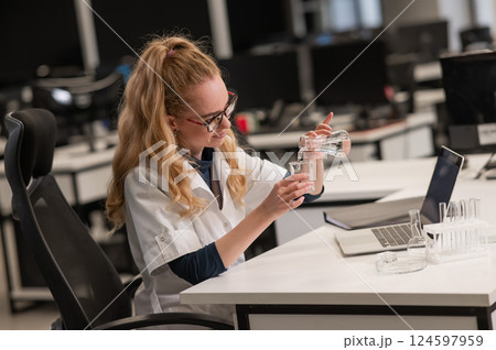 Caucasian woman in a medical gown doing laboratory experiments. Caucasian woman in a medical gown doing laboratory experiments. 124597959