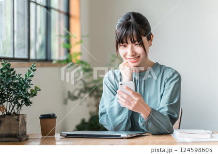 カフェでスマホを使う若いアジア人ビジネスウーマン カフェでスマホを使う若いアジア人ビジネスウーマン 124598605