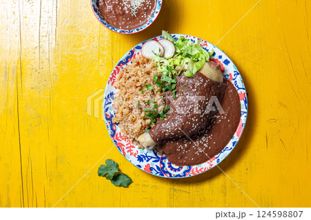 Delicious mole poblano chicken with rice on yellow background 124598807