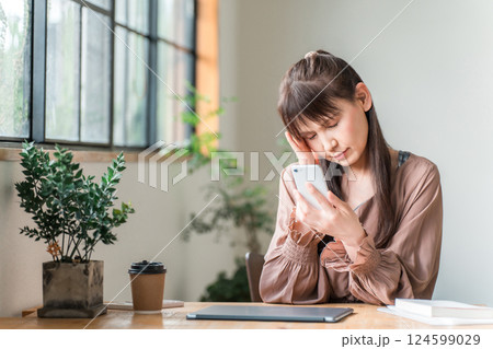 カフェでスマホを使う中高年の女性（眼精疲労,スマホ老眼,疲れ目,頭痛） 124599029