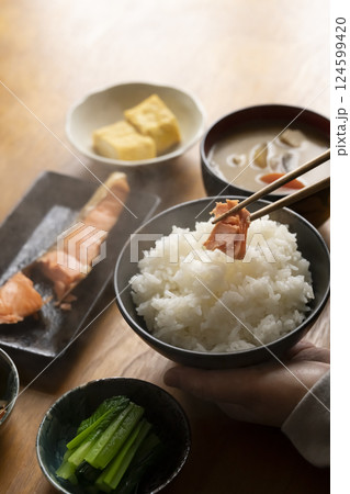 朝食のおかずを箸で持ち上げる 朝食のおかずを箸で持ち上げる 124599420