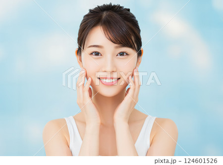 両手を頬にあてて微笑む若い女性のビューティーイメージ 124601526