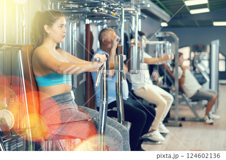 Young girl doing chest press in exercise machine in gym Young girl doing chest press in exercise machine in gym 124602136