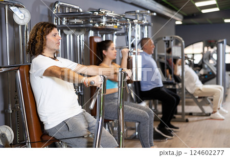 Sporty man doing chest press on execise machine in gym 124602277