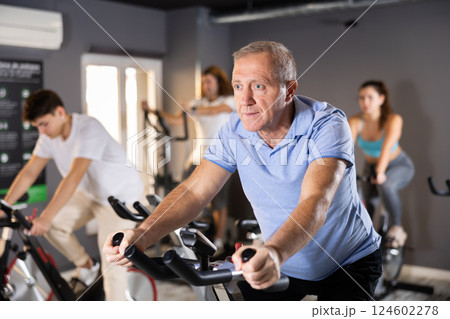 Elderly man doing cardio training on stationary bike in gym 124602278