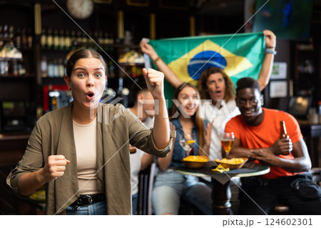 Excited young girl cheering for Brazilian team while watching match in sports bar Excited young girl cheering for Brazilian team while watching match in sports bar 124602301