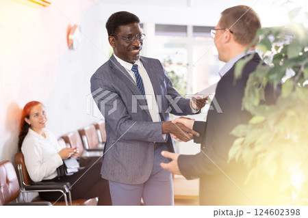 Two adult man shaking hands in reception 124602398