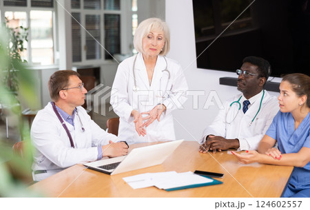 Mature female doctor speaks at meeting of colleagues and tells reports on condition of patients. 124602557