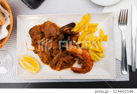 Hake in sailor style - fish cooked in thick tomato sauce with addition of mussels and shrimp 124602596