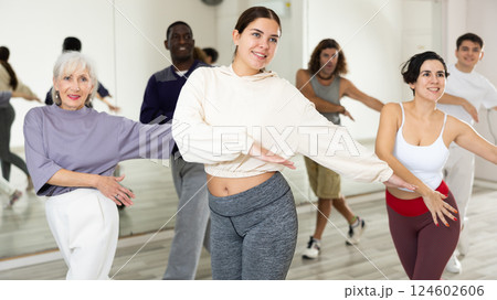 Smiling girl learning dynamic dances in group choreography class Smiling girl learning dynamic dances in group choreography class 124602606